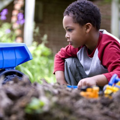 African-American boy playing
	    in a sandbox